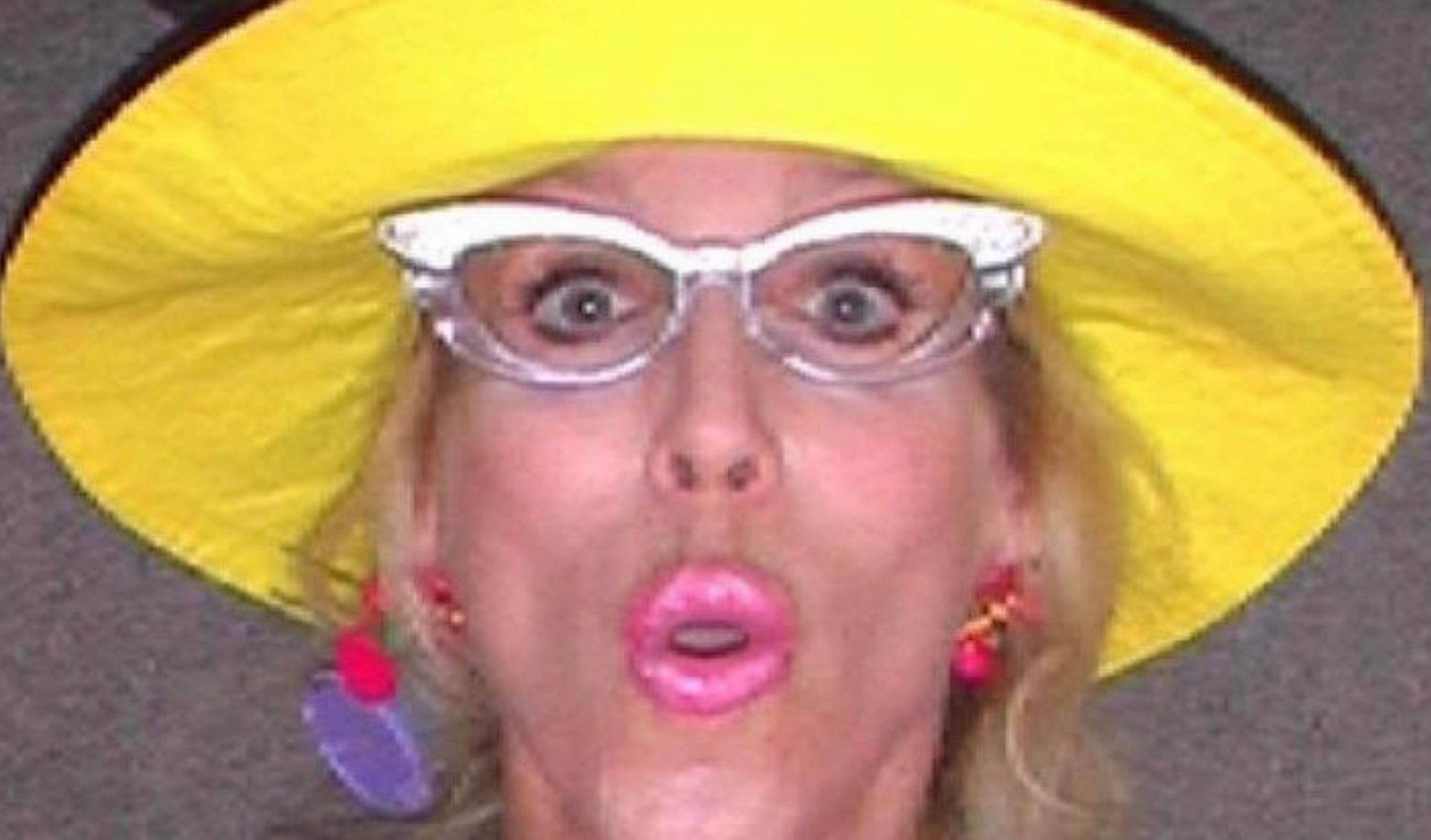 Dottie Dexter talking, silver eyecat glasses, pink lipstick, hair curler, colored earrings
